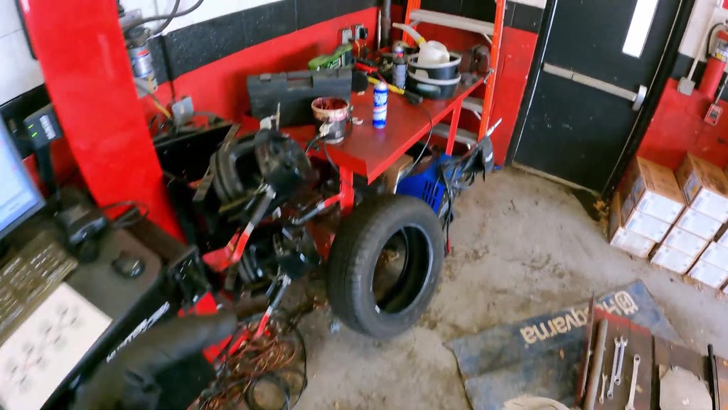 The mechanic returned the impact wrench, stowed a long pry bar, and carried a liquid jug to the rear workbench. The jug
